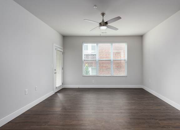 A room with a ceiling fan and a window with blinds.