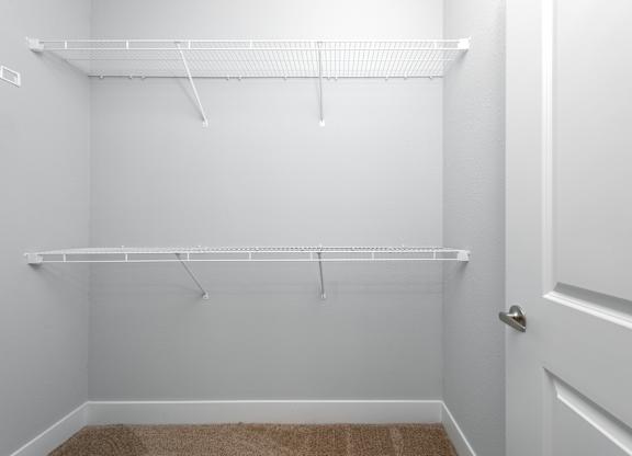 A white closet with a carpeted floor and a white door.