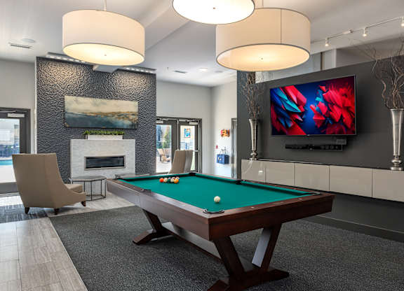 A room with a pool table and a television mounted on the wall.