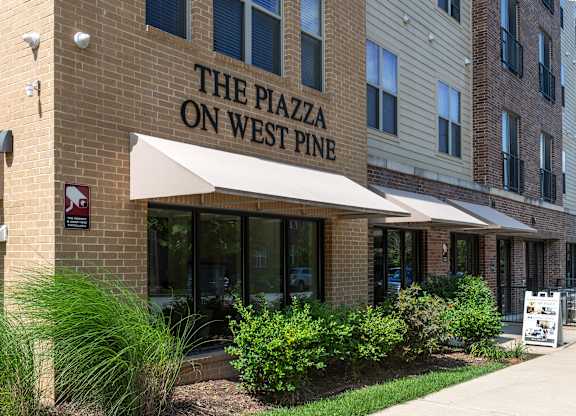 The Plazza on West Pine is a multi-story building with a beige facade and a white awning.