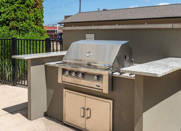 A beige outdoor kitchen with a grill and oven.