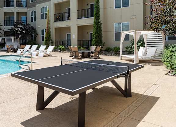 A black table tennis table is in the middle of a concrete patio.