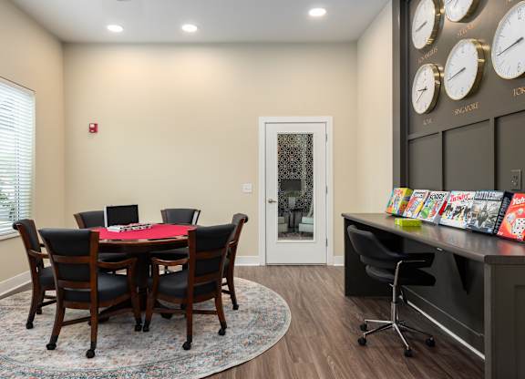 A conference room with a table and chairs and a wall of clocks.