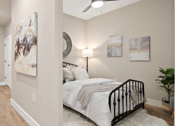 A bedroom with a bed, a ceiling fan, and a painting on the wall at The Oliver Apartments, Missouri