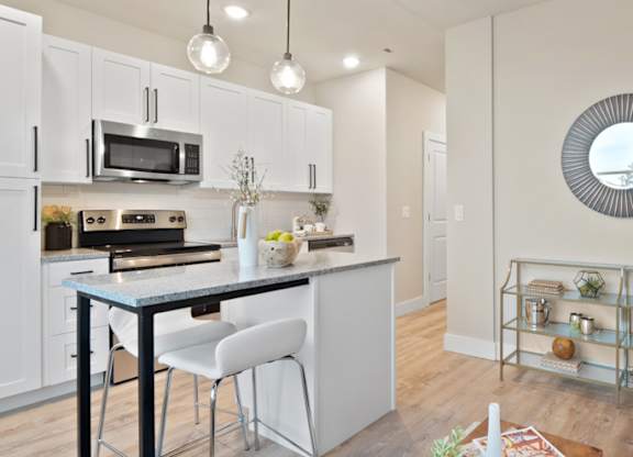 A modern kitchen with white cabinets and a black countertop at The Oliver Apartments, Olivette, 63132
