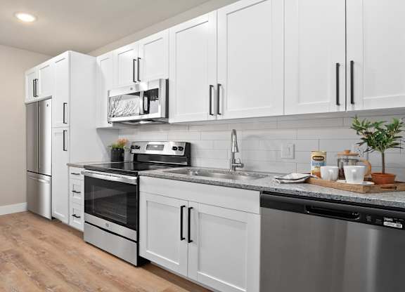 A modern kitchen with stainless steel appliances and white cabinets at The Oliver Apartments, Missouri, 63132