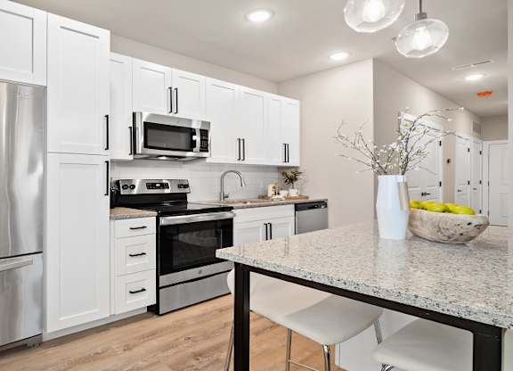 A modern kitchen with stainless steel appliances and white cabinets at The Oliver Apartments, Olivette, MO, 63132