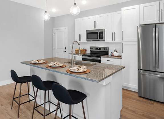A kitchen with a bar area and a refrigerator at The Oliver Apartments, Olivette, MO
