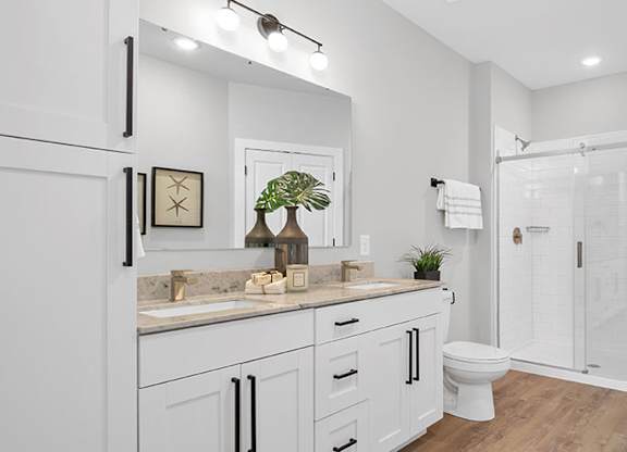 A white bathroom with a sink, toilet, and shower. at The Oliver Apartments, Olivette, MO, 63132