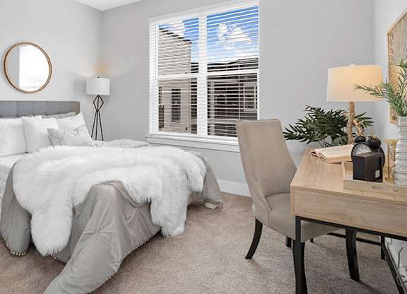 A bedroom with a grey bedspread and a round mirror on the wall at The Oliver Apartments, Missouri