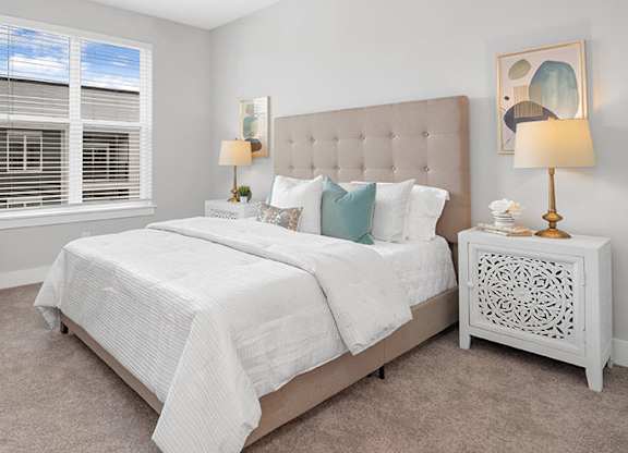 A bedroom with a large bed, a chair, and a table with a vase and a plant on it at The Oliver Apartments, Olivette