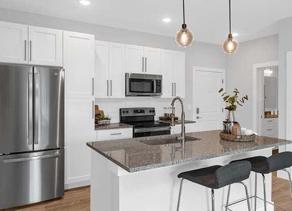 A modern kitchen with a granite countertop and stainless steel appliances at The Oliver Apartments, Missouri, 63132