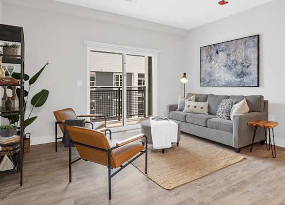 A living room with a grey couch, a brown chair, and a brown rug at The Oliver Apartments, Olivette, Missouri