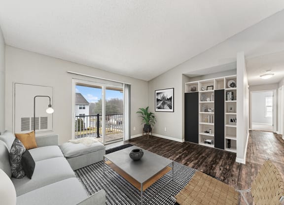 Model Living Room with Wood-Style Flooring and Patio Accessibility at Commons at Haynes Farm Apartments in Shrewsbury, MA.