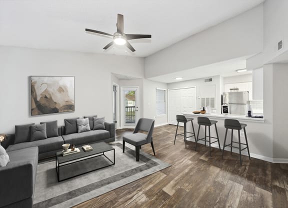 Model Living Room with Wood-Style Flooring and View of Kitchen at Retreat at Crosstown Apartments in Riverview, FL.