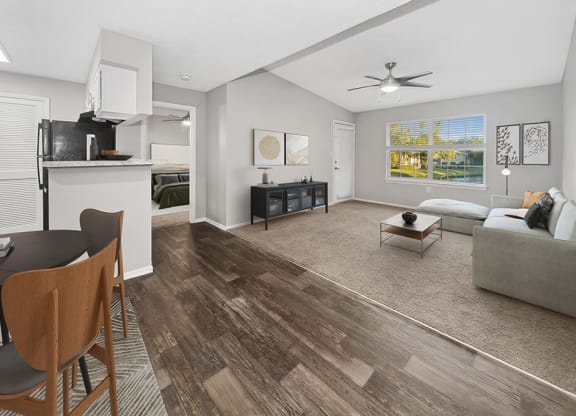 Model Dining Room and Kitchen Area with Wood-Style Flooring and View of Living Room at Walden Lake Apartments in Plant City, FL.