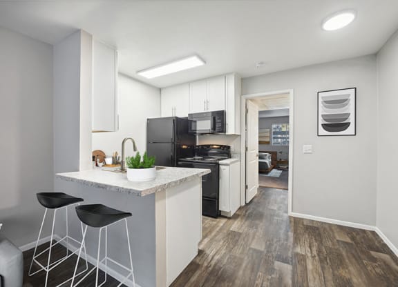 Model Kitchen with White Cabinets and Wood-Style Flooring at Country Club Verandas Apartments located in Mesa, AZ.