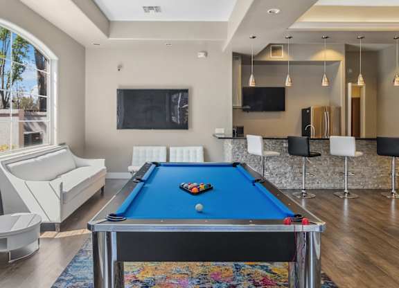 A pool table is in the middle of a room with a couch and a TV.