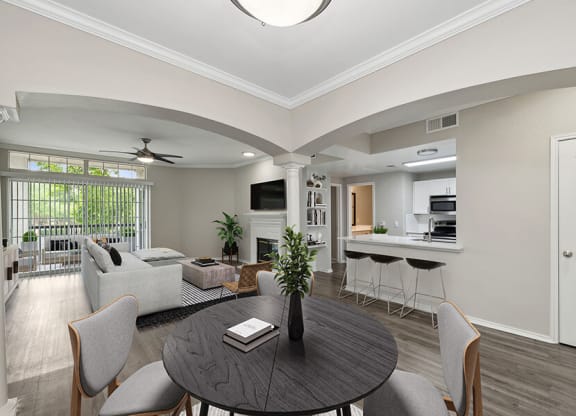 Model Dining Room with Wood-Style Flooring and View of Living Room/Kitchen Area at Allure North Dallas Apartments located in Dallas, TX.