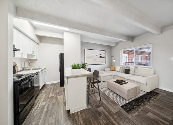 Model Living Room with Wood-Style Flooring and View of Kitchen at Esprit at Cherry Creek Apartments in Glendale, CO.