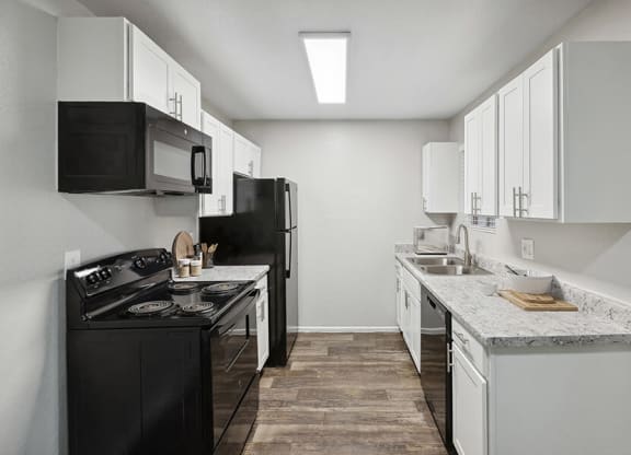 Model Kitchen with White Cabinets and Wood-Style Flooring at Solano Springs Apartments located in Tucson, AZ.