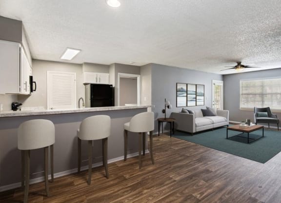 Model living room and kitchen with bar seating and wood floors