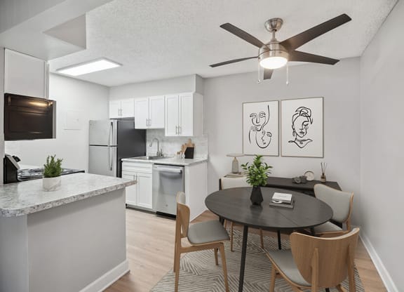 Model Dining Room and Kitchen with White Cabinets and Wood-Style Flooring at Waterfront Apartments in Lakewood, CO.