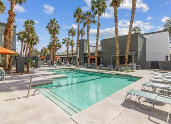 a swimming pool with palm trees and a building in the background