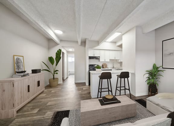 Model Living Room with Wood-Style Flooring and View of Kitchen at Esprit at Cherry Creek Apartments in Glendale, CO.