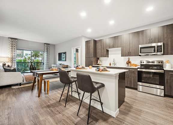 Model Kitchen with Dark Wood Cabinets and Wood-Style Flooring at Glen 91 Apartments located in Glendale, AZ.