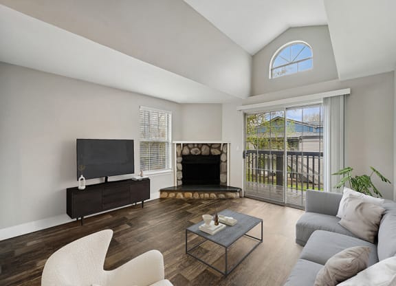 Model Living Room with Wood-Style Flooring, a Fireplace and Patio Accessibility at Central Flats Apartments in Kent, WA.