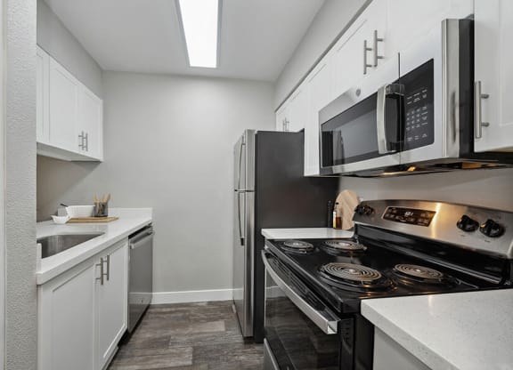 Model Kitchen with White Cabinets and Wood-Style Flooring at Crystal Creek Apartments located in Phoenix, AZ.