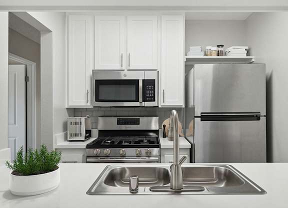 Model Kitchen with White Cabinets and Wood-Style Flooring at Fullerton Hills Apartments located in Fullerton, CA.