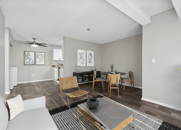 Model Living Room with Wood-Style Flooring and View of Kitchen/Dining Area at Liberty Creek Apartments in Aurora, CO.