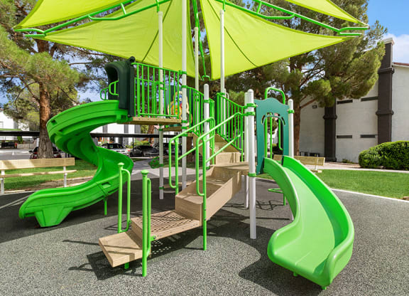 Community Playground with two Slides and a Green Canopy at Meadow Ridge Apartments in Las Vegas, NV.
