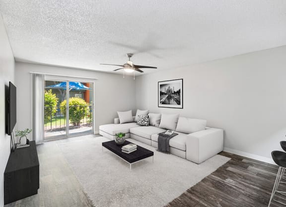 Model Living Room with Wood-Style Flooring and Patio Accessibility at Indigo Park Apartments located in Albuquerque, NM.