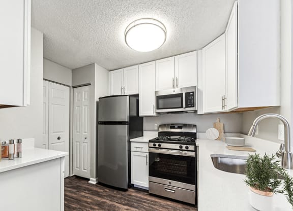 Model Kitchen with White Cabinets and Wood-Style Flooring at Commons at Haynes Farm Apartments in Shrewsbury, MA.