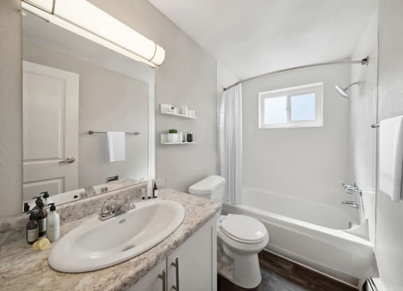 Model Bathroom with White Cabinets, Wood-Style Flooring and Shower/Tub at Esprit at Cherry Creek Apartments in Glendale, CO.