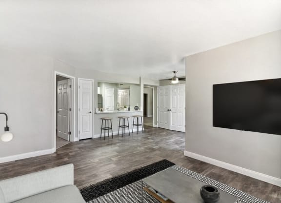 Model living room with a television and a kitchen in the background