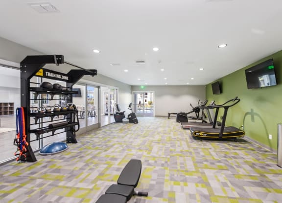 a workout room with weights and cardio equipment and a wall mounted tv