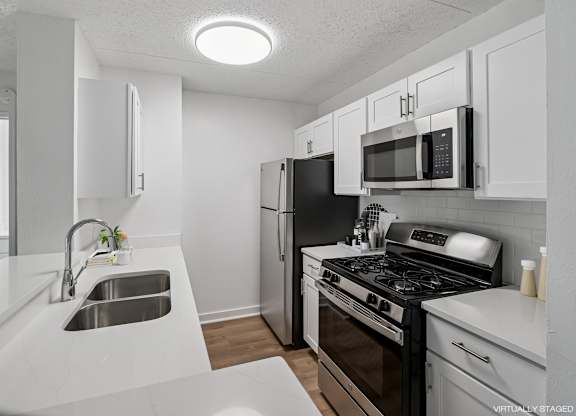 Model modern kitchen with black appliances and white cabinets.