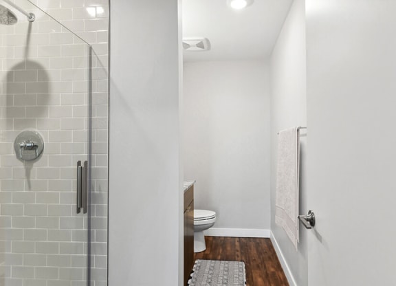 Model Bathroom with Wood-Style Flooring, Dark Oak Cabinets & Shower/Tub at Seven Skies Apartments located in Sandy, UT.