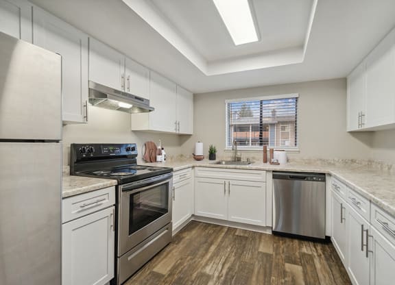 Model Kitchen with White Cabinets and Wood-Style Flooring at Grammercy Apartments located in Renton, WA.