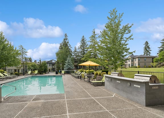 Community Swimming Pool & BBQ Area with Lounge Furniture at The Club Apartments located in Hillsboro, OR.