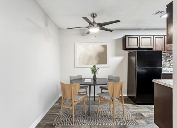 Model Dining Room with Wood-Style Flooring and View of Kitchen at Paramont Apartments in Duluth, GA.