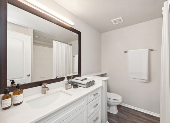 Model Bathroom with Wood-Style Flooring, White Cabinets & Shower/Tub at Allure North Dallas Apartments located in Dallas, TX.