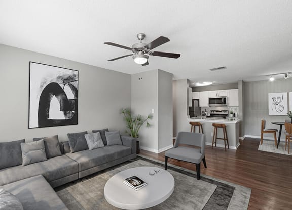 Model Living Room with Wood-Style Flooring and View of Kitchen/Dining Area at Fountains Lee Vista Apartments in Orlando, FL.