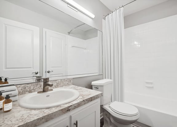 Model Bathroom with Wood-Style Flooring, White Cabinets & Shower/Tub at Rosehill Preserve Apartments located in Orlando, FL.