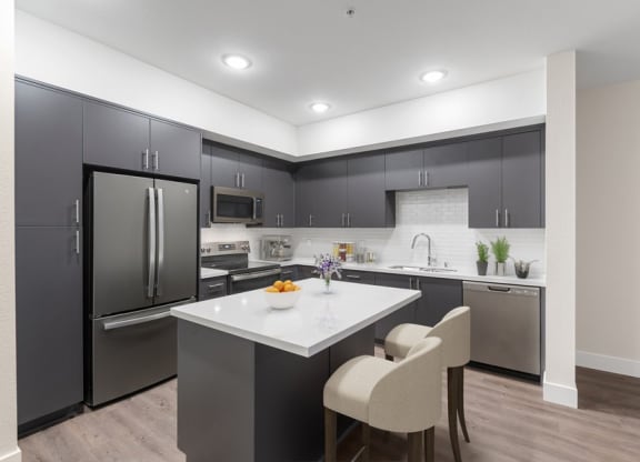 Model kitchen with dark cabinetry and bar