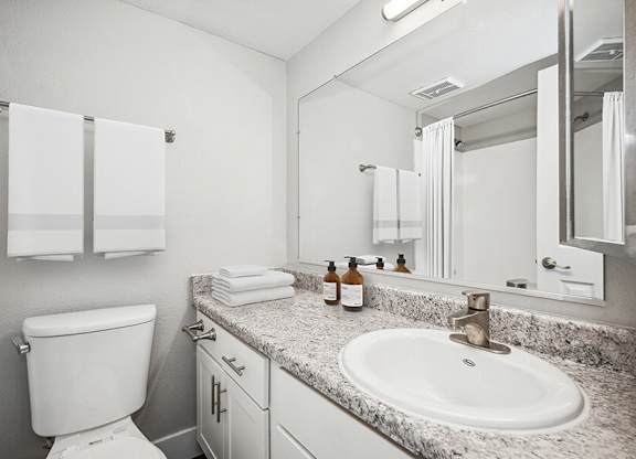 Model Bathroom with White Cabinets and Wood-Style Flooring at Stillwater Apartments located in Glendale, AZ.